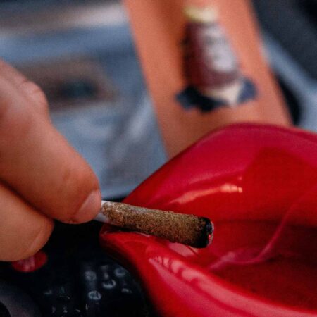 Smoldering infused pre roll next to a red ashtray