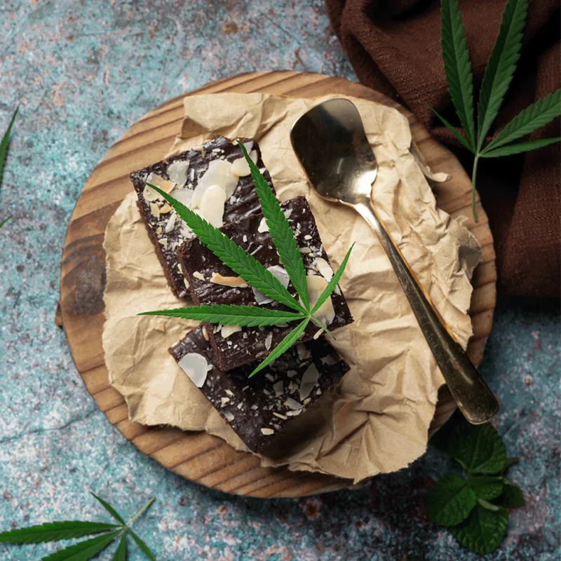 There’s brown chocolate bread on the table with coconut cannabis oil and a metal spoon