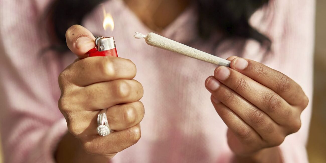 A person holds a lighter and a joint