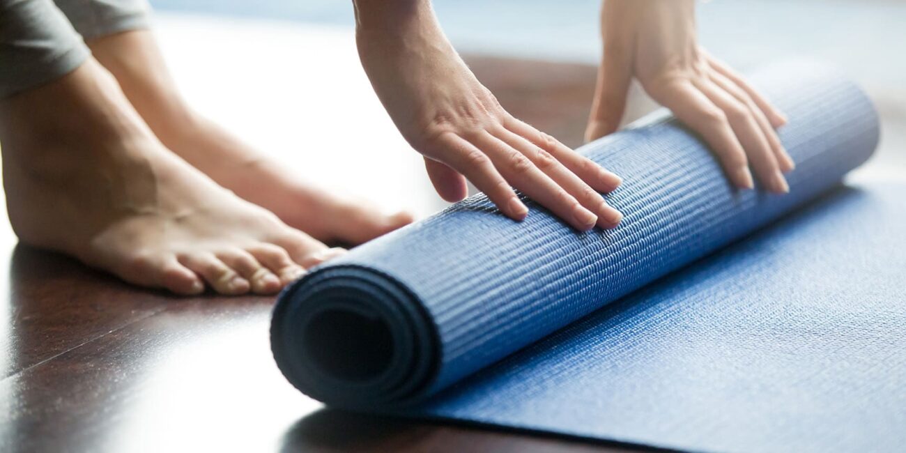 A person rolls up yoga mat