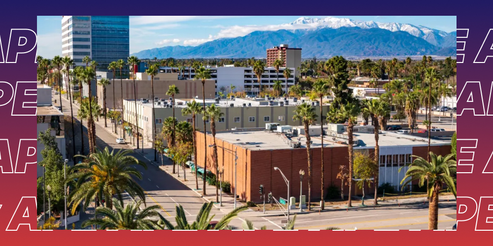 Aerial view of downtown San Bernardino with palm trees and snow-capped mountains in the background.