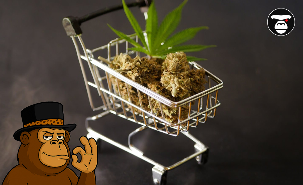 A miniature shopping cart filled with dried cannabis buds and a fresh cannabis leaf resting on top.