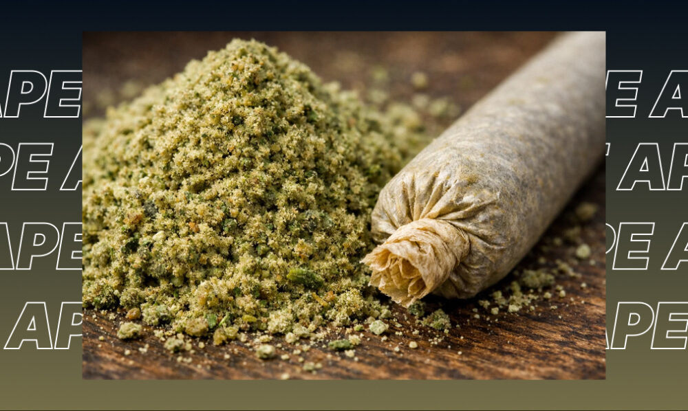 Macro view of a pile of kief or cannabis extract next to a hand-rolled joint on a wooden surface.