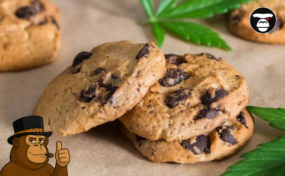 A stack of soft chocolate chip cookies on parchment paper with cannabis leaves