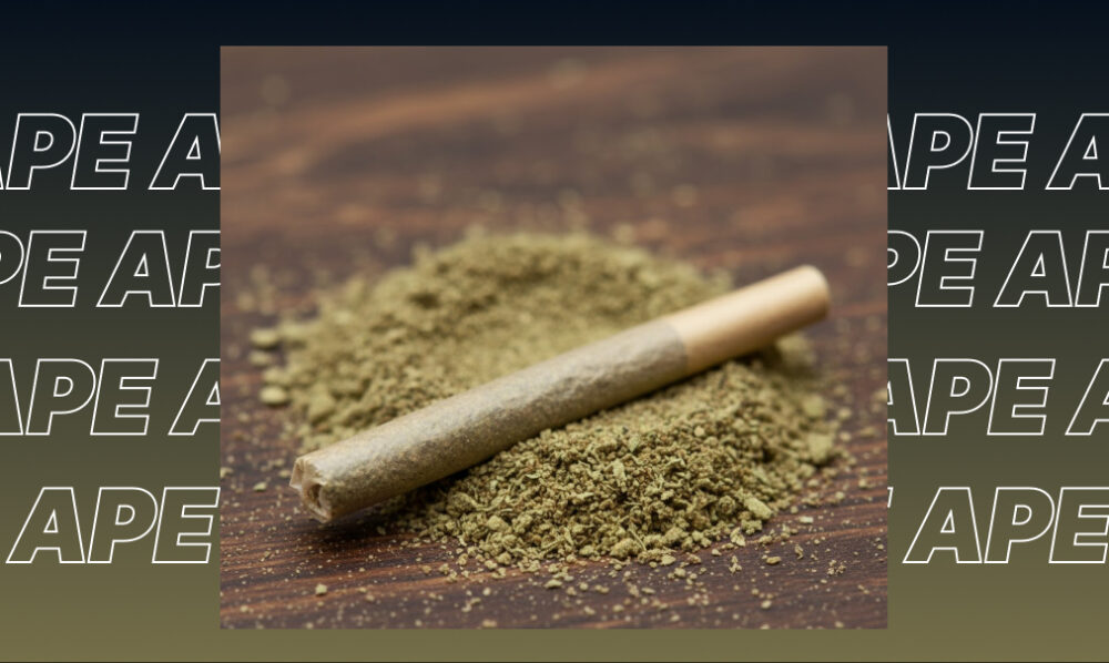A pre-rolled joint sitting on a pile of ground cannabis flower.