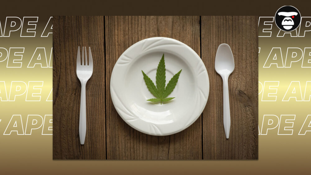 A single green cannabis leaf placed in the center of a white plate with a fork and spoon.