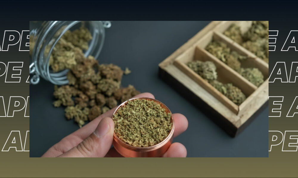 A hand holding a copper grinder filled with ground green cannabis next to a wooden stash box.